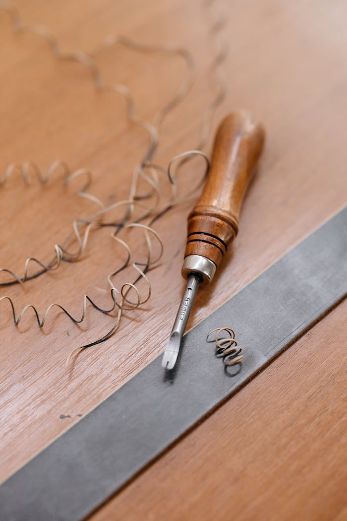 Close-up of a woodworking tool with spiral shavings on a wooden surface, showcasing craftsmanship.